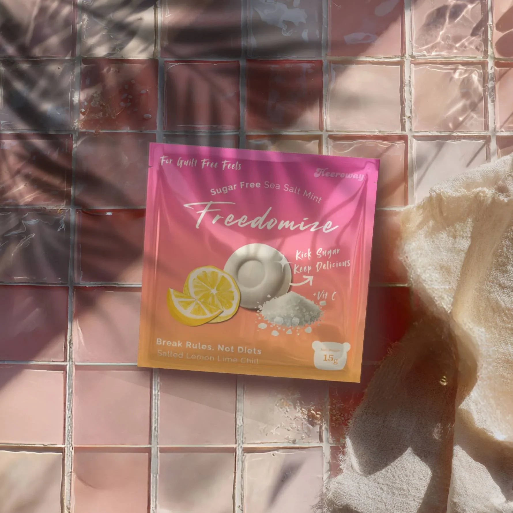 Freedomize Salted Lemon Lime Chill Sugar-Free Sea Salt Mint pouch placed on glossy pink tiled surface with soft shadows and a fabric cloth beside it.