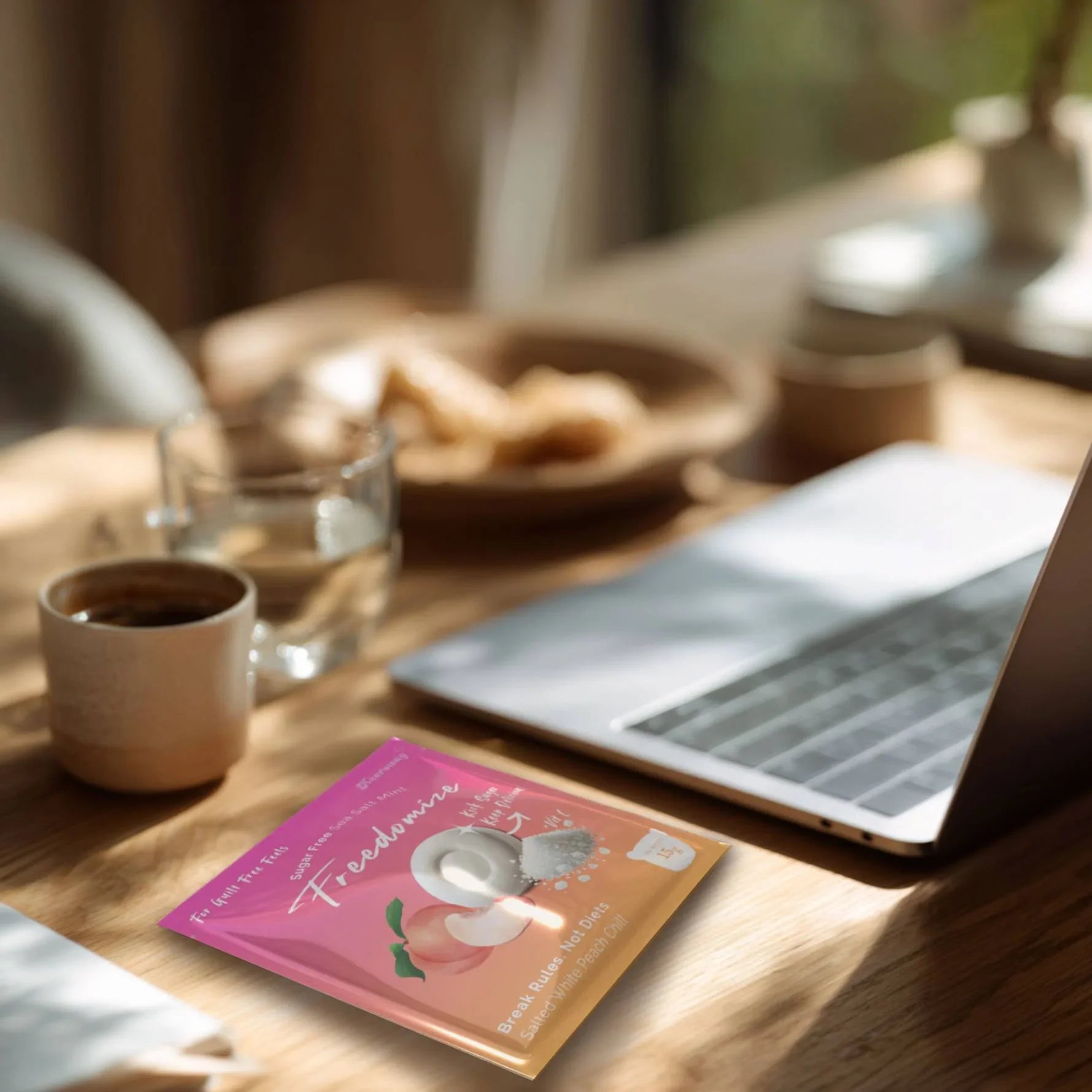Freedomize Salted White Peach Chill sugar-free sea salt mint pouch on a wooden desk beside a coffee cup and laptop, captured in natural light.