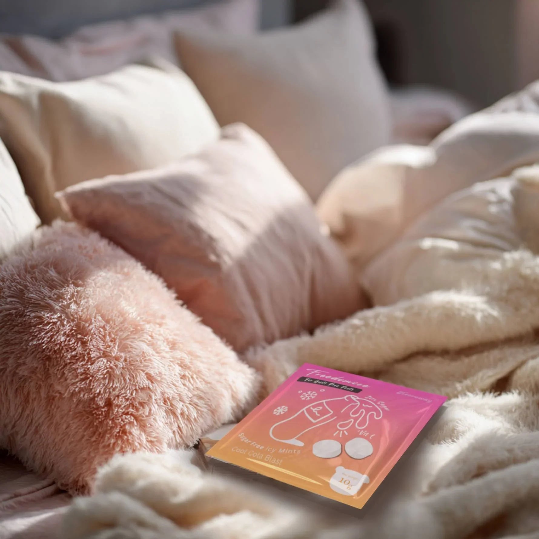Freedomize Cool Cola Blast Sugar-Free Icy Mints pouch placed on a cozy bed with soft pink pillows, blanket, and a coffee cup nearby in product page.