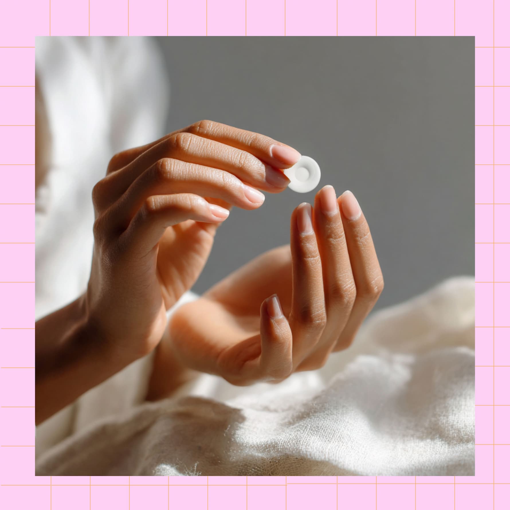 loseup of hands holding freedomize sugar free mint tablet with soft fabric background and pink grid border