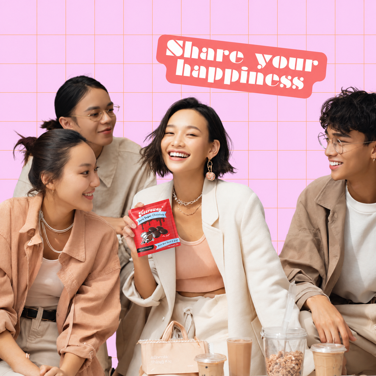 Four young adults smiling and laughing in a brightly lit indoor setting with a pink grid wall. One woman in the center holds up a red packet of Heeroway Sugar free chocolate and a red banner at the top reads 'Share your happiness'.