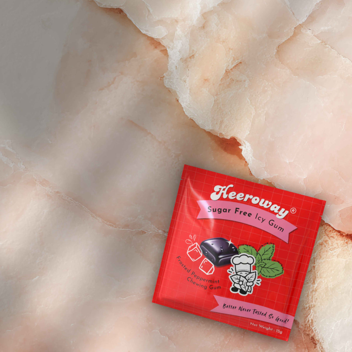 A packet of Heeroway Sugar Free Peppermint Icy Gum placed on a textured pink and white stone surface.
