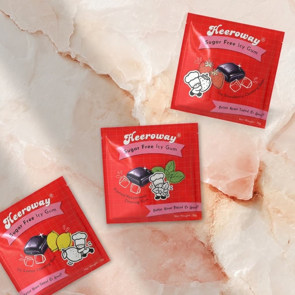 Three red packets of heeroway Sugar Free Icy Gum candy arranged on a light pink and white marbled surface.