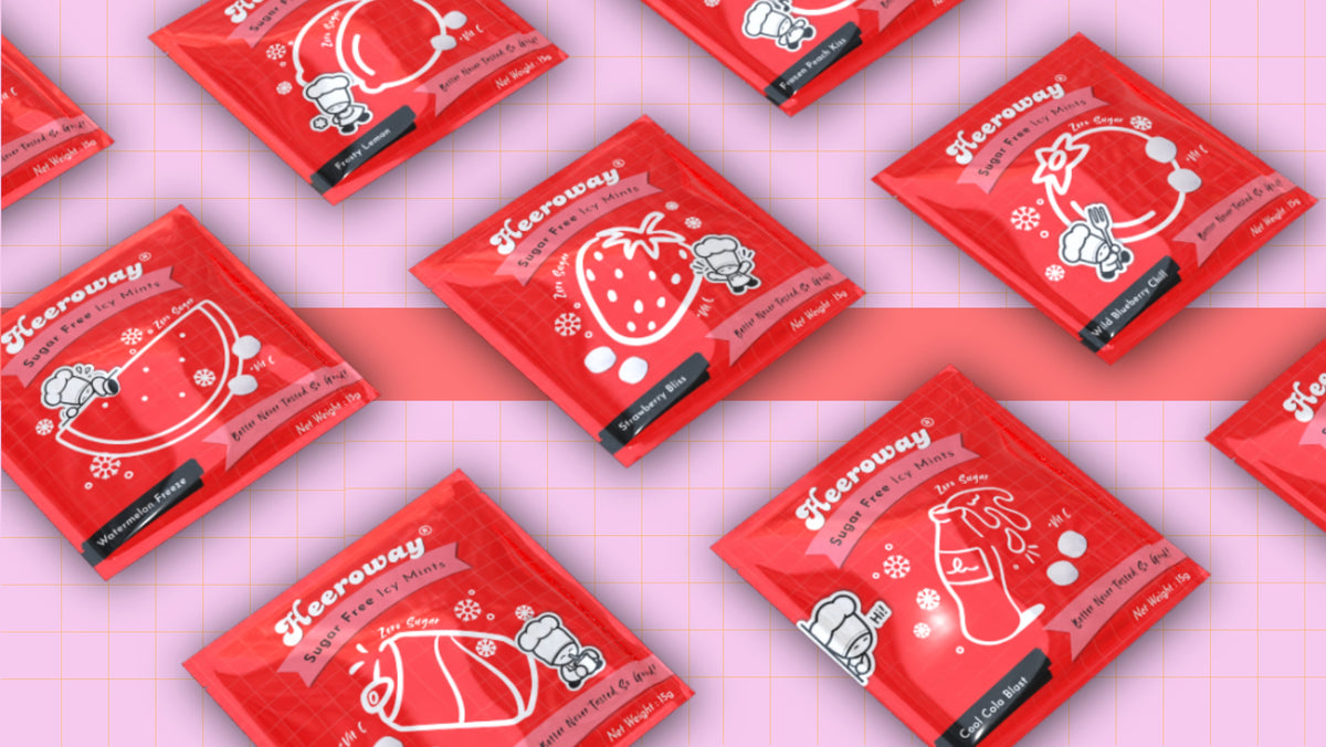 Flat lay arrangement of Heeroway sugar free icy mints packaging in various fruity flavors on a pink background.
